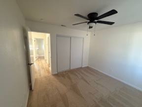 A room with a ceiling fan and light, and a doorway leading to another room.