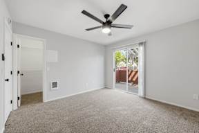 A room with a ceiling fan and carpeted floor.