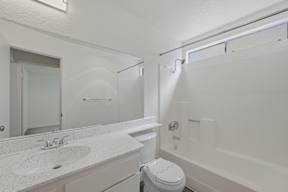 A white bathroom with a toilet, sink, and bathtub.