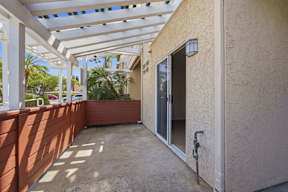 A patio with a white pergola and a red fence.