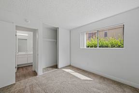 A white room with a window and a door leading to another room.