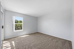 A room with a window showing a view of trees and a building outside.