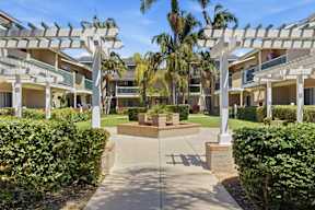 A sunny day at a residential complex with a walkway leading to a courtyard.
