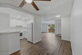 A white kitchen with a wood floor and a ceiling fan.