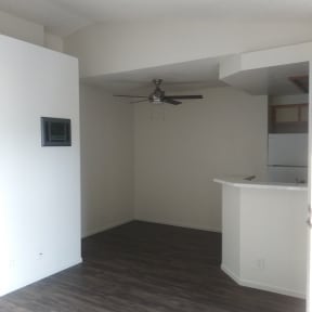 Living room view of dining area with ceiling fan and adjacent kitchen at La Costa Seashore Apartments in Carlsbad, CA.
