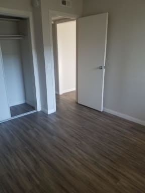 Bedroom with hardwood flooring and large closet at Tulip Street Apartments in Escondido, California.