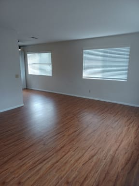Living room with hardwood flooring and large windows for lots of natural light in apartment home at Juniper Street Apartments in Escondido, California.