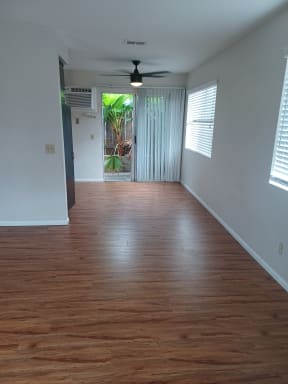 Living room and dining room with ceiling fan and sliding door to patio at Juniper Street Apartments in Escondido, California.