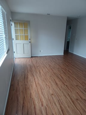 Front door into living room with hardwood flooring at Juniper Street Apartments in Escondido, California.