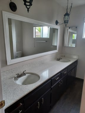 Bathroom with double vanity with lots of cabinet space and window at Juniper Street Apartments in Escondido, California.