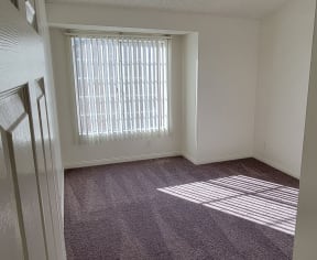 Carpeted bedroom with large window at Northwood Apartments in Upland, California.