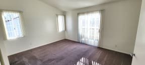 Large carpeted bedroom with private porch and lots of natural light at Northwoods Apartments in Upland, California.