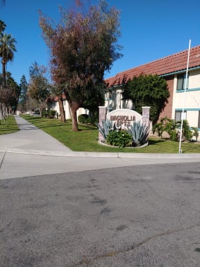 Mature trees and landscaping in front of Magnolia Apartments in Riverside, California.