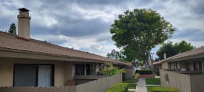 Mature trees and gardens along walkways at Las Casitas Apartments in Riverside, California.