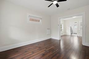 A room with a ceiling fan and wooden floors.