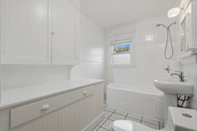 A white bathroom with a tub, sink, and toilet.