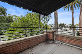 A balcony with a black railing and a brick wall.