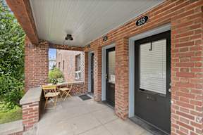 A patio with a table and chairs is on the front porch of a house.