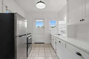 A kitchen with black appliances and white cabinets.