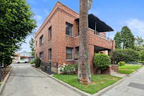 A red brick house with a tree in front.