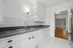 A kitchen with white cabinets and a black countertop.