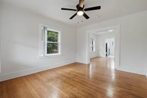 A room with a ceiling fan and wooden flooring.