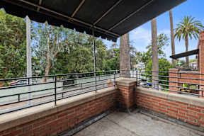 A balcony with a brick wall and metal railing.