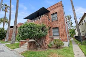 A red brick house with a tree in front.