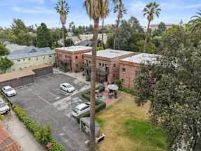 A parking lot with cars and palm trees in front of a building.
