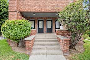 A red brick house with a black front door and steps leading to the entrance.