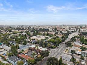 A cityscape with buildings, roads, and trees under a clear sky.