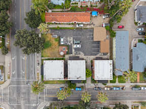 A parking lot with cars and a building with a red roof.