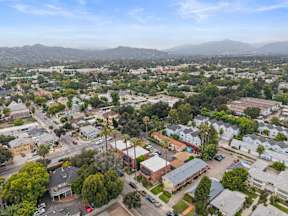 A bird's eye view of a residential area with houses, trees, and roads.