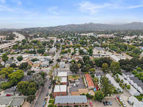 A bird's eye view of a residential area with houses, trees, and a parking lot.