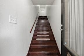 A long flight of wooden stairs leads to a door.