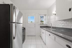 A kitchen with a black refrigerator and white cabinets.