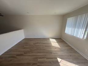 A room with wooden flooring and a window with blinds.
