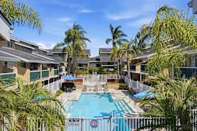 A pool surrounded by palm trees and apartment buildings.