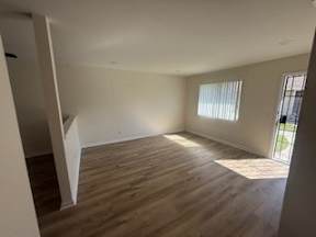 A room with wooden flooring and a window with blinds.