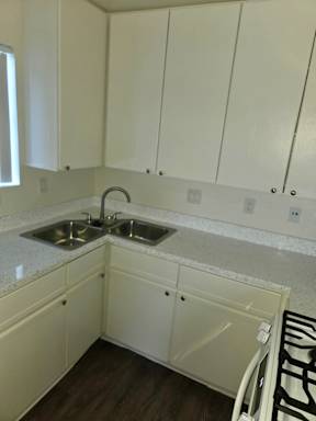 A kitchen with white cabinets and a sink.