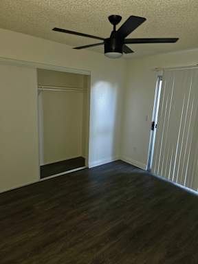 A room with a ceiling fan and sliding door.