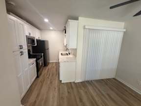 A kitchen with white cabinets and a black fridge.