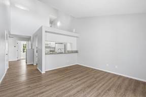 A spacious kitchen and living room with hardwood floors and white walls.