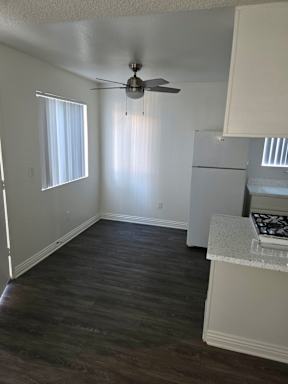 A room with a ceiling fan and a window with blinds.