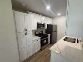 A kitchen with white cabinets and a marble counter top.