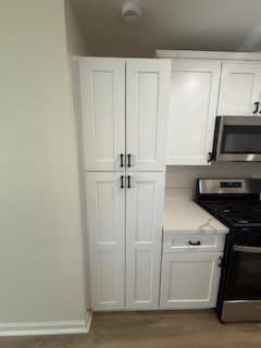 A kitchen with white cabinets and a black stove.