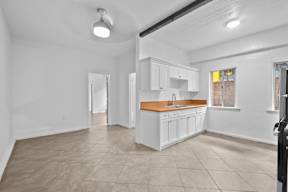A white kitchen with a wooden countertop and white cabinets.