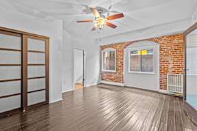 A room with a ceiling fan and wooden flooring.