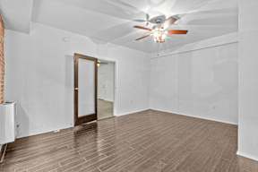 A room with a ceiling fan and wooden flooring.