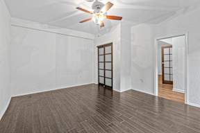 A room with a ceiling fan and wooden flooring.